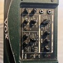 Zelený kytarový kombo zesilovač značky VOX, model MINI 5 Rhythm. Na ovládacím panelu jsou různé potenciometry a přepínače pro nastavení efektů, rytmu…