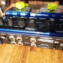 Modrý kytarový looper Digitech JamMan Loop Sample Stereo. Zařízení má několik ovládacích knoflíků, tlačítka a dvě žluté nožní spínače. Na zadní stran…