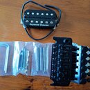 Na dřevěném povrchu je položen černý humbucker s bílým nápisem Seymour Duncan. Vedle něj se v plastových sáčcích nachází imbusový klíč, čtyři šrouby…