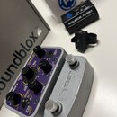 Na fotografii jsou dva efekty značky SOURCE AUDIO v stříbrném kovovém provedení. Levý pedál má fialový ovládací panel s několika otočnými potenciomet…