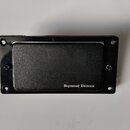 Černý kytarový snímač s krytem. V pravém dolním rohu je bílý nápis Seymour Duncan. Snímač je umístěn v černé rámečku s otvory pro šrouby. Povrch kryt…