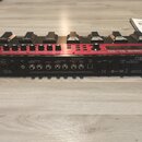 Červený loop station BOSS RC-50 s černými tlačítky a ovládacími prvky. Na zadní straně jsou viditelné vstupy a výstupy s nápisy INPUT, PHANTOM, MIC,…