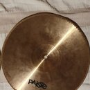 Kulatý činely z mosazného kovu s jemným žlutým leskem. Na povrchu je černý nápis PAiste a pod ním menší text MADE IN SWITZERLAND. Povrch vykazuje mír…