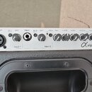 Detail ovládacího panelu černého reproduktoru s bílým podkladem ovladačů. Panel obsahuje dva vstupy (input 1 s XLR konektorem a input 2 s jackem), kn…
