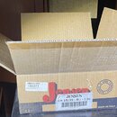 Otevřený hnědý karton s nápisem Jensen. Na štítku je uveden kód 186571 a text Cone Speaker 2CH 1035-B Chicago 10" Graphene/Paper 35. Na bílé nálepse…