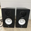 Dva černé regálové reproduktory s bílými membránami basových jednotek a černými výškem. V dolní části každého reproduktoru je umístěno logo Yamaha. P…