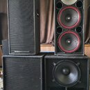 Čtyři velké černé reproduktory v bednách. Horní levý má na spodní hraně nápis CERWIN-VEGA!. Horní pravý obsahuje jeden stříbrný vysokofrekvenční repr…