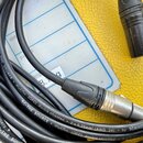 Černý audio kabel s kovovými konektory. Na plášti kabelu je opakovaně bílý nápis SC-THE SOURCE Highflex (OFC) double shielded 2 x 0.25mm² (AWG 24) by…