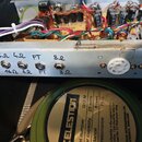 Fotografie zachycuje vnitřek elektronického zařízení s viditelným zapojením kabelů a součástek na desce. Na kovové liště jsou čtyři konektory s ručně…