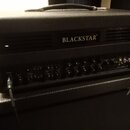 Černý kytarový zesilovač s nápisem BLACKSTAR na předním panelu. V dolní části se nachází řada ovládacích knoflíků a vstup INPUT, do kterého je zapoje…