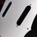Bílá plechová nebo plastová krytka (pickguard) s dvěma dlouhými oválnými výřezy pro snímače. V povrchu jsou rozmístěny malé kulaté otvory pro šrouby.…