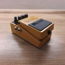 Zlatý kytarový efekt pedál s černým spínacím tlačítkem. Na horní straně je nápis Acoustic Simulator RC-1 a logo BOSS. Na boku jsou dva vstupní konekt…