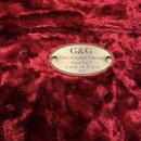 Detail vnitřku pouzdra s červeným plyšovým povrchem. Uprostřed je připevněna oválná kovová pláška s nápisem G&G, „The Original Vintage Case Co.“, MAD…