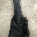Černý softcase (obal) na kytaru z textilního materiálu. Obal je vybaven ramenním popruhem s plastovou sponou a zipem v horní části. Povrch vykazuje m…