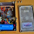 Fotografie zachicuje otevřený kytarový efekt v žlutém kovovém šasi a oddělené víko. Uvnitř jsou vidět elektronické součástky, zapojení kabelů a modrá…