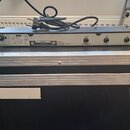 Šedý elektronický přístroj s nápisy KORG, MODEL: CP-2 a SERIAL No. 003420. Na zadní straně jsou tři konektory označené jako MUTE, OUT a IN, dále nápi…