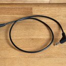 Černý audio kabel s konektory na obou koncích. Na jedné straně je pravuhlý 6,35mm jack a na druhé straně cylindrický napájecí konektor. Kabel je v do…