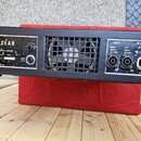 Zadní strana černého zesilovače s kovovým šasi a ventilační mřížkou. Na levé straně je nápis SEAK, POWER AMPLIFIER, 220 V ~ 50 Hz a PA 410. Pravá str…