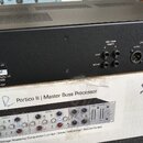 Černý rackový procesor s ventilací na horní straně, umístěný na kartónovém obalu. Na zadní straně jsou viditelné konektory a nápisy: SIDE CHAIN INSER…