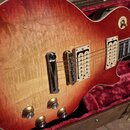 Elektrická kytara s tělem v červeno-žlutém sunburst provedení a viditelnou strukturou dřeva. Nástroj má dva humbuckery s krémovými rámečky a čtyři zl…