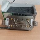 Krytovaný humbucker s kovovým krytem a dvěma řadami poladitelných šroubů. Na levé straně je nalepená štítková nálepka s textem 38118 TB-15 20220516 a…