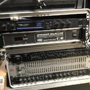 Dvě stohované rackové skříně s audio vybavením. Horní rack obsahuje zařízení Yamaha REV100 Digital Reverb Processor a Speaker Selector Microprocessor…