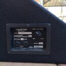 Fotografie zachycuje zadní panel černého reproduktorového boxu potaženého látkovým povrchem. Na panelu je nápis CELESTION CR Series™, MODEL CR-102M,…