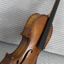 Detailní pohled na hřifo a horní část těla smyčkového nástroje, pravděpodobně housle, v hnědém lakovaném provedení. Na těle jsou viditelné f-otvory a…