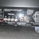 Zadní panel černého zesilovače s ovládacími prvky a nápisy. Je zde vidět logo TSC™, sekce POWER SOAK s přepínači 18 W, 5 W a 1 W, oraz nápis SPEAKER.…