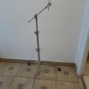 Stříbrný kovový stativ s teleskopickým stojanem a nastavitelní ramenem. Na konci ramene je umístěn černý držák. Povrch kovových částí je lesklý, bez…