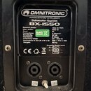 Fotografie zachycuje zadní panel černého subwooferu. Je zde viditelný štítek s nápisy OMNITRONIC, www.omnitronic.com a Subwoofer-System BX-1550 spolu…
