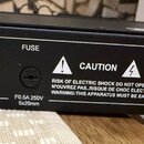 Záběr na zadní stranu černého elektronického zařízení. Je zde vidět štítek s nápisy FUSE, Power Input: AC 230V~50Hz, 0.5A Max., F0.5A 250V 5x20mm a v…