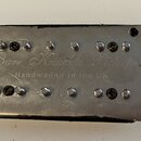 Kovový snímač k elektrické kytáře stříbrné barvy s dvěma řadami šesti šroubů. Na povrchu je vyryto „Bare Knuckle Pickups“ a pod tím nápis „Handwound…