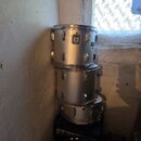 Tři stříbrné bubny v kovovém provedení naskládané na sebe. Na spodním bubnu je vidět otvor pro kabel nebo úpravu. Povrch nástrojů vykazuje známky běž…