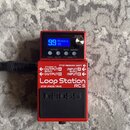 Červený efekt pedál Loop Station RC-5 značky BOSS. Na přední straně je modrý displej s nápisem 99 Memory 99 a ovládací tlačítka RHYTHM, SETUP, MEMORY…
