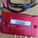 Červené kovové zařízení s nápisy behringer U-CONTROL UCAR02 CONCEIVED AND DESIGNED BY BEHRINGER GERMANY. MADE IN CHINA. Na spodní straně je bílá nále…