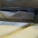 Detailní záběr na černý elektronický hudební přístroj s displejem. Na povrchu displeje je viditelná prasklina v podobě tenké bílé čáry. Vedle displej…