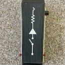 Kytarový efekt v černé barvě s žebrovaným povrchem. Na horní straně je bílý symbol připomínající elektronickou schéma s vlnovkou, trojúhelníkem a pře…