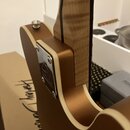 Detail zadní strany hřdelu a těla elektrické kytary v bronzové barvě s krémovým lemováním. Na kovovém krytu hřdelu je vyryto logo a nápis "Harley Ben…