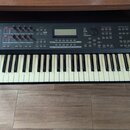 Černý digitální klavír s bílými a černými klávesami. Na levé straně panelu je logo YAMAHA a na pravé nápis MOX6. Horní ovládací panel obsahuje disple…