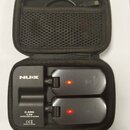 Černý bezdrátový systém v přepravním pouzdře s USB kabelem. Na základní jednotce je bílý nápis NUX a štítek s textem C-5RC 5.8G WIRELESS SYSTEM, CE z…