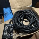 Černá stagebox s osmi vstupy XLR, ze kterých vychází svazek černých kabelů. V horní části stageboxu jsou viditelné nápisy 1 až 8 u jednotlivých vstup…