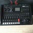 Černý digitální sekvenční přístroj značky ZOOM, model R8 s nápisem Recorder:Sampler Interface:Controller. Zařízení obsahuje displej, několik ovládací…