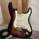 Elektrická kytara s tónem sunburst a bílým pickguardem. Má tři snímače, pětipozicovní přepínač a tři bílé ovládací knoflíky. Na kytaru není vidět žád…