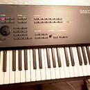 Černý digitální klavír s bílými klávesami. V pravém horním rohu je nápis OASYS a pod ním menší text Open Architecture Synthesizer Station. Panel obsa…