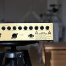 Zadní strana zlatého hudebního zařízení s řadou konektorů. Jsou zde nápisy L, Return, R, L, Send, R, Post Stereo Effects Loop, Return, Send, Side Cha…