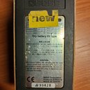 Zadní strana efektového pedálu značky BOSS. Na spodní části je nápis „BOSS Corporation Products of Roland MADE IN TAIWAN“ a sériové číslo „JJ 99428“.…