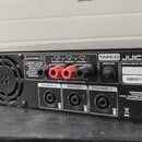 Černý rackový zesilovač značky TAPCO s názvem modelu JUICE. Na zadním panelu jsou vidět vstupy INPUT 1 a INPUT 2, tři dvojice výstupů SPEAKER CONNECT…