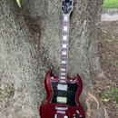 Kytara s tmavě červeným lakem a černým pickguardem, opřená o kmen stromu. Na hlavě je žlutý nápis "Lancer". Nástroj má dva humbuckery, tři ovládací k…