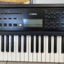 Černý digitální klavír značky YAMAHA. Nástroj má bílé a černé klávesy a ovládací panel s různými tlačítky pro výběr hlasů (VOICE) a stylů (SONG / STY…